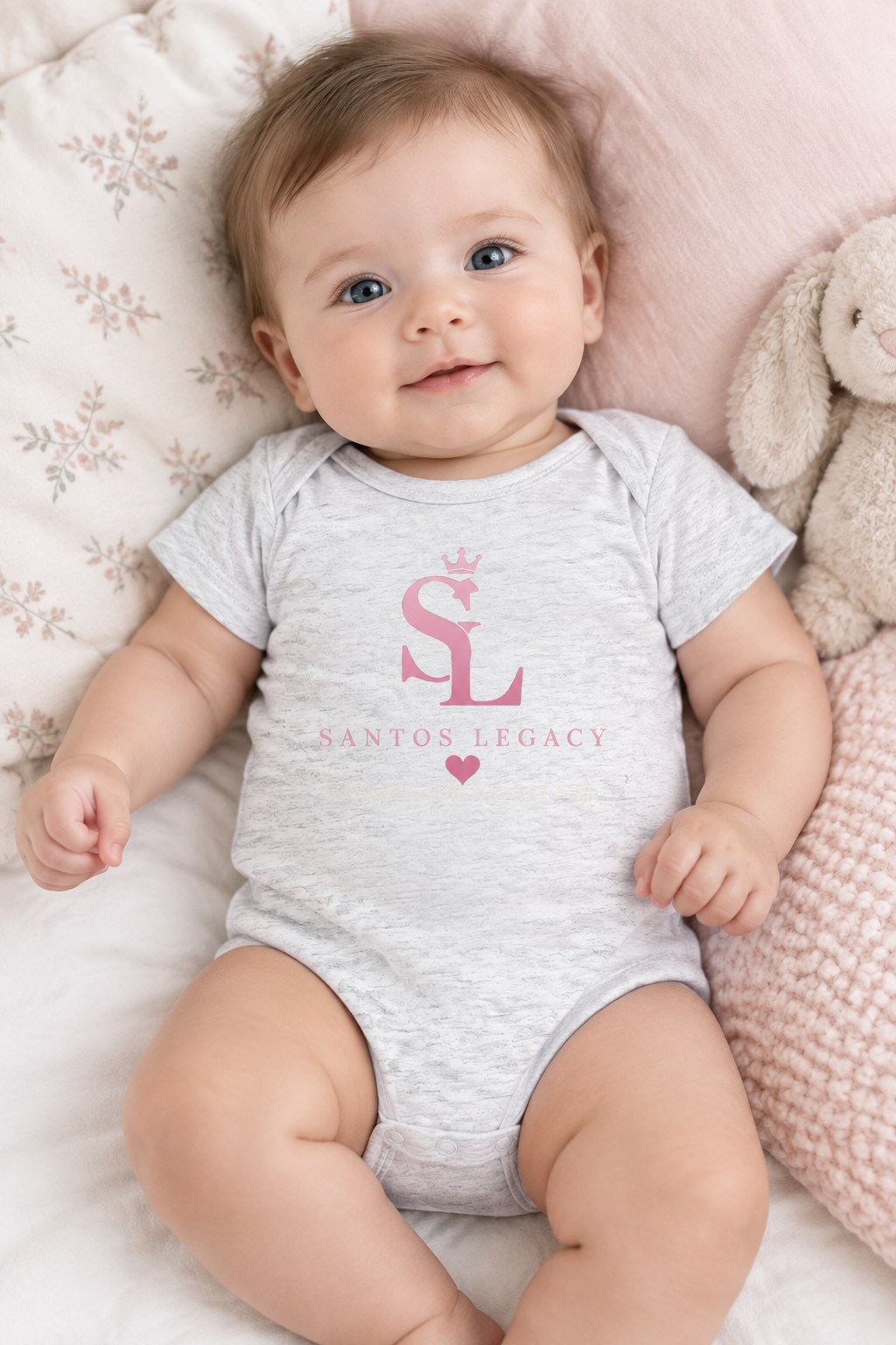 Baby wearing the Santos Legacy Little Legacy Baby jersey bodysuit lying on soft pillows in a pastel nursery