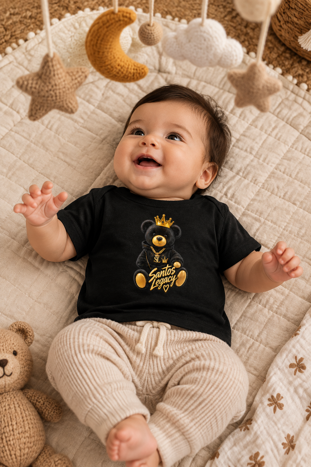 Baby wearing the Santos Legacy Baby Jersey Short Sleeve Tee on a quilted play mat under a knit mobile