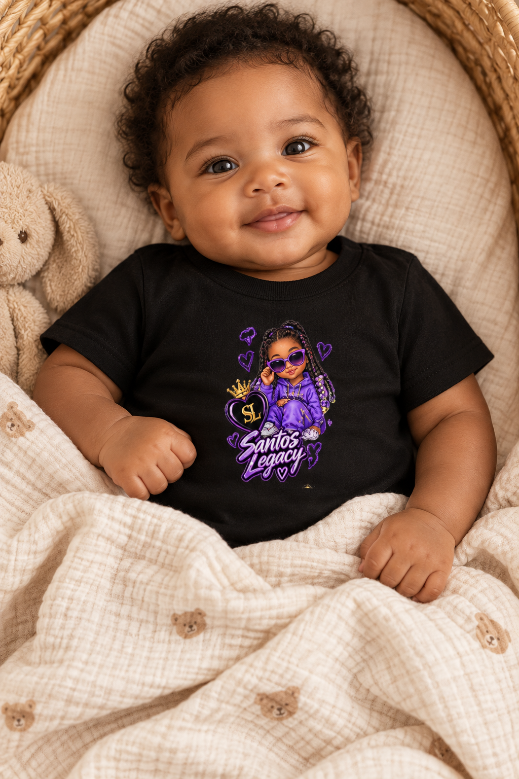 Baby wearing the Santos Legacy Baby Jersey Short Sleeve Tee in a soft cradle with a muslin blanket