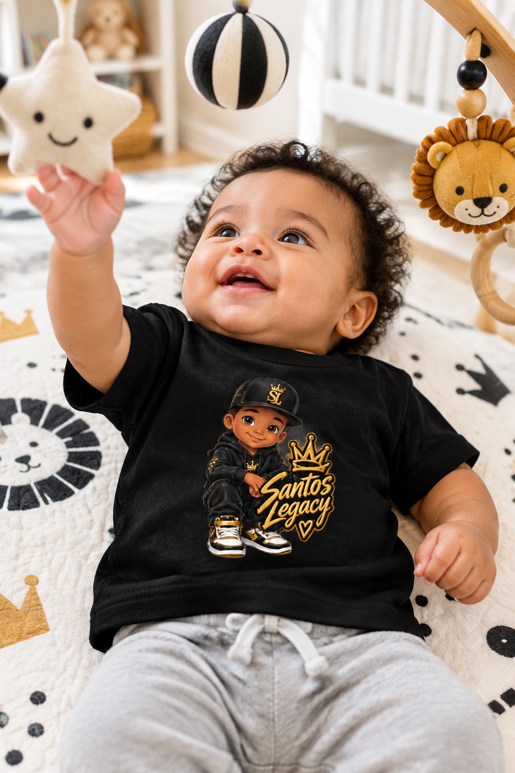 Baby wearing the Santos Legacy Baby Jersey Short Sleeve Tee on a play mat reaching for a hanging toy gym