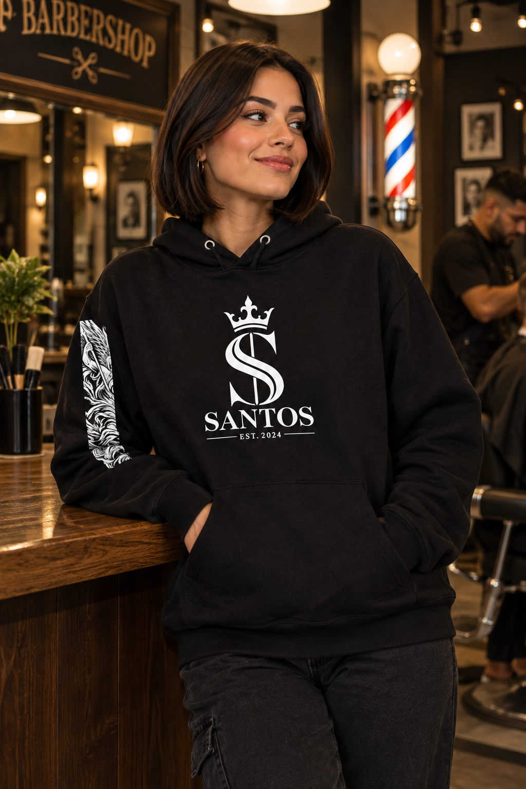 Woman wearing the Santos Legacy Signature Premium Unisex Hoodie at a barbershop counter